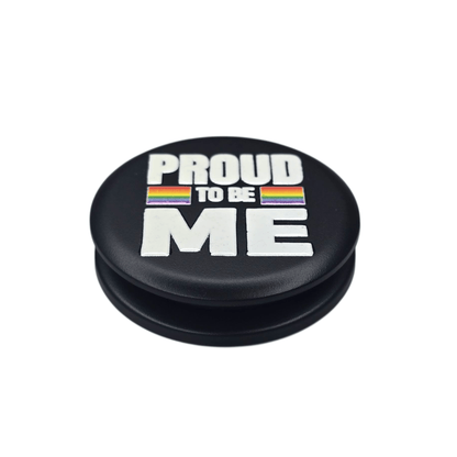 Sateenkaaren väreillä koristeltu musta puhelinpidike, jossa teksti "Proud to be me"
